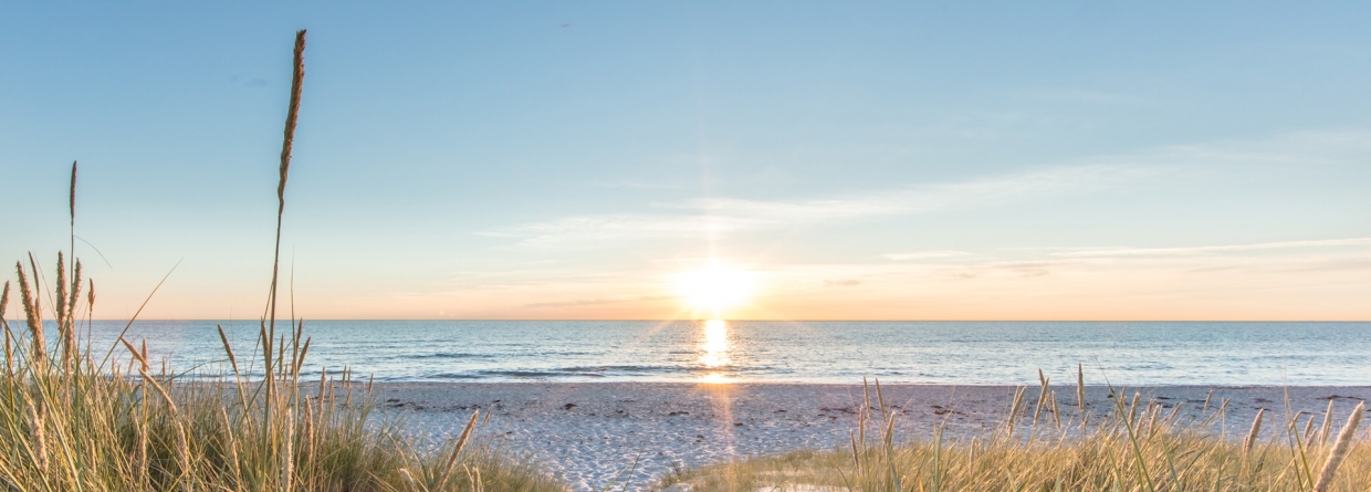 Een ondergaande zon vanaf de duinen met uitzicht op zee