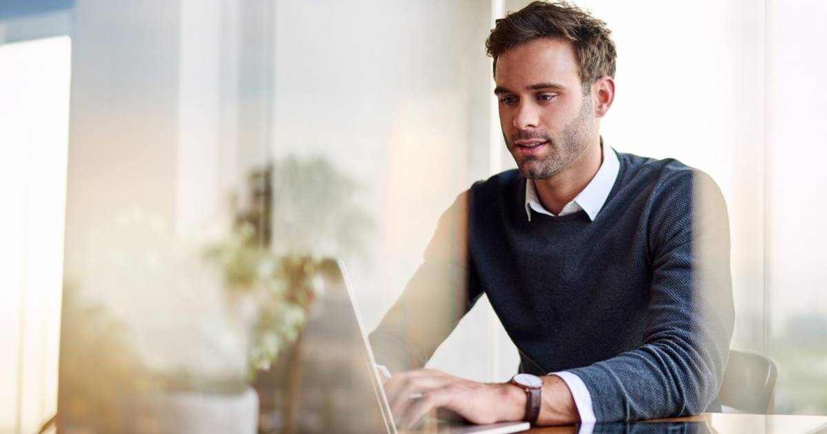 Jonge ondernemer is vanuit huis aan het werk op zijn laptop