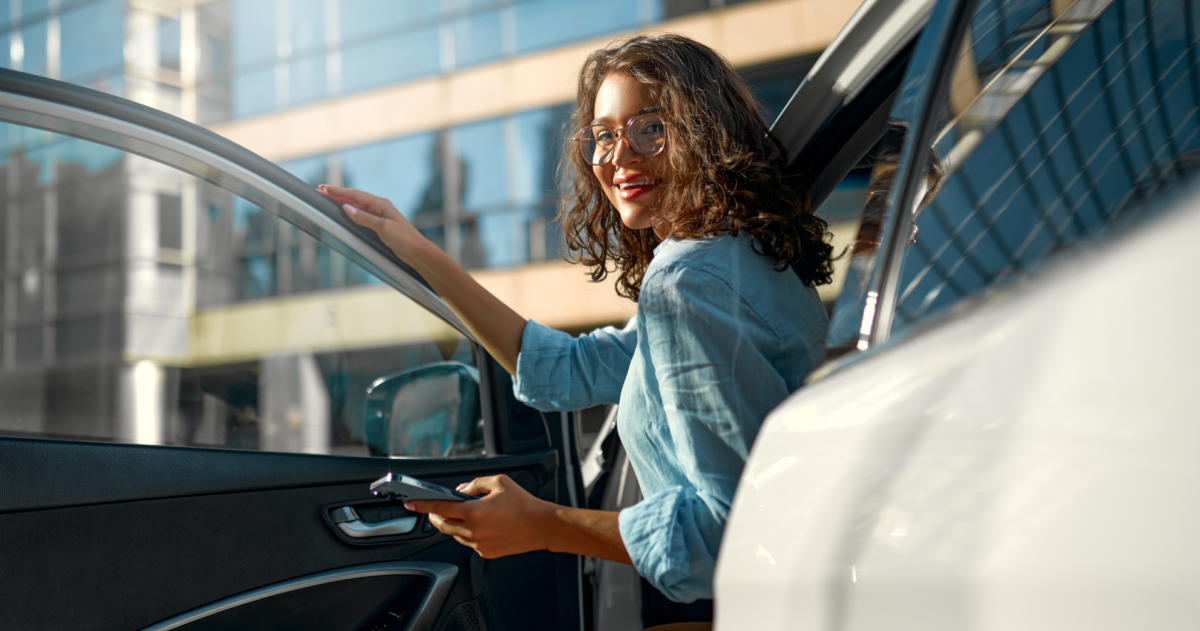 Jonge vrouw naast haar auto op straat